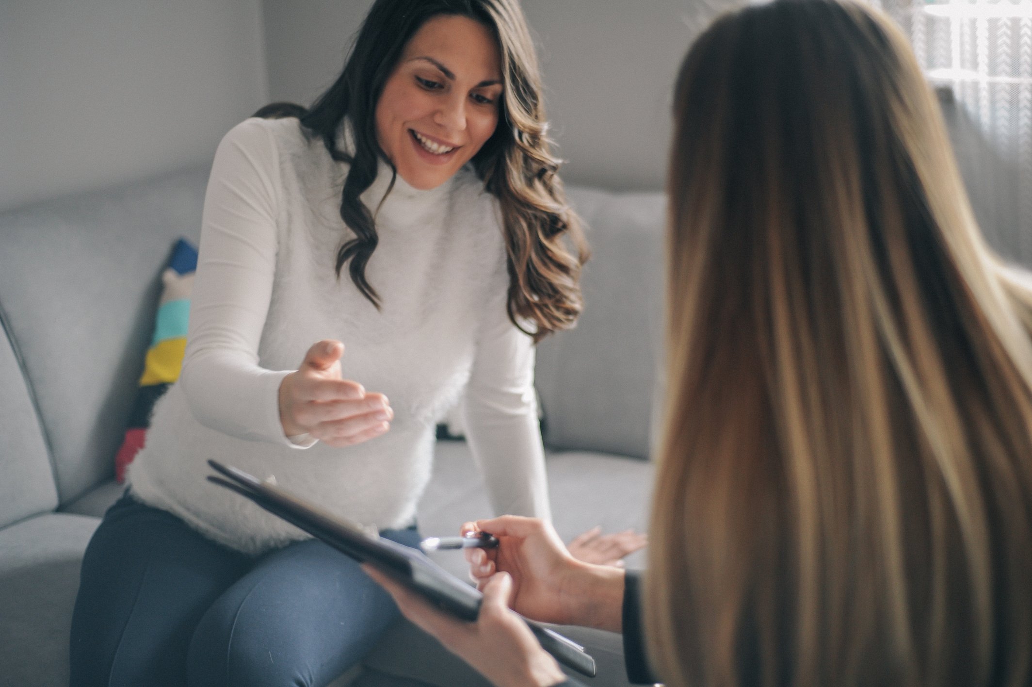 Young pregnant woman having home meeting with a female counsellor